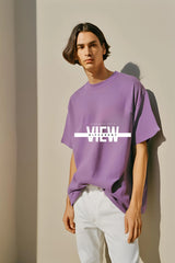 A person wearing a purple round neck half sleeve t-shirt with the text 'NEVER GIVE UP' printed on the front.